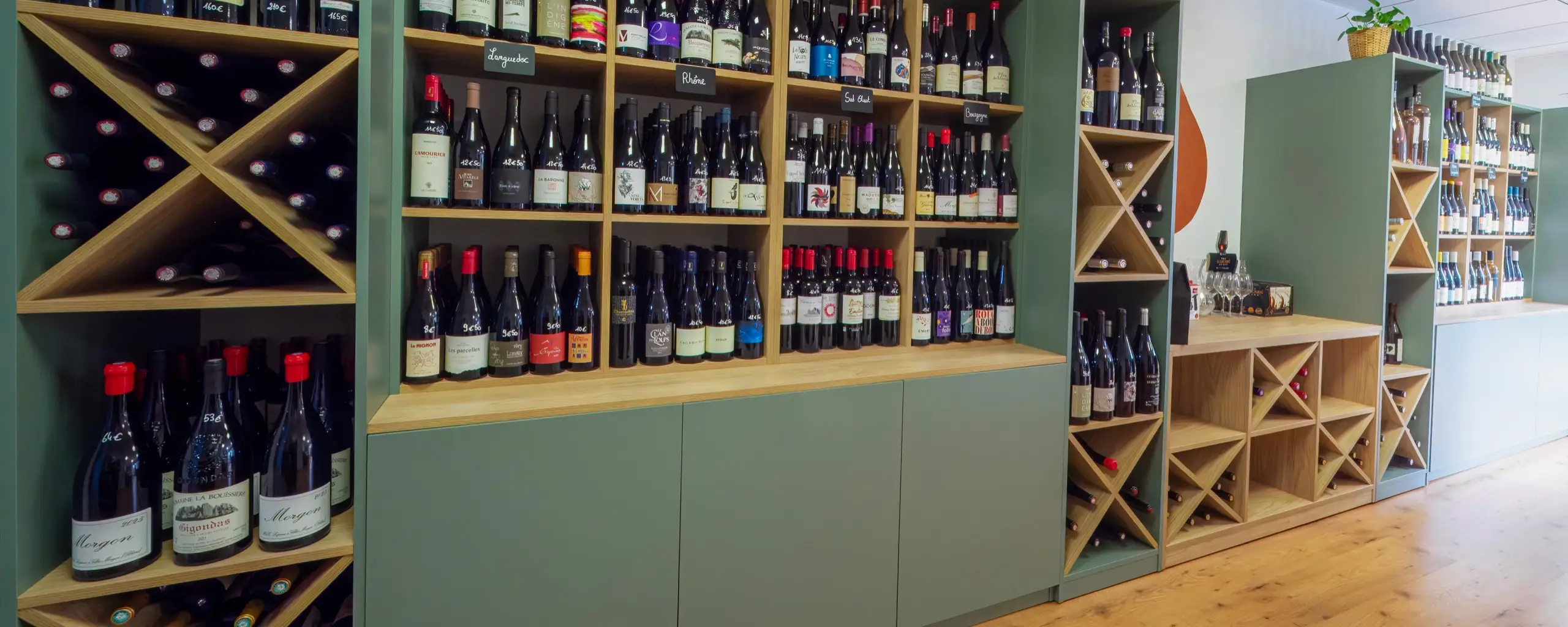 Intérieur de La Cave Nectar à Léguevin, rayon vins sur meubles vert bouteille et bois